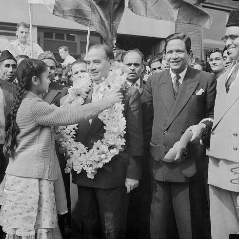 Huseyn Shaheed Suhrawardy (1892 - 1963), the Prime Minister of Pakistan, receives a garland from 12-year-old Jehanara Choudhry, upon his arrival at London Airport, 24th June 1957. Suhrawardy is in the UK to attend the Commonwealth Prime Ministers' Conference which opens the next day, 24th June 1957.